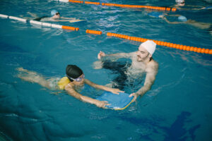 SSI-certified swim coach teaching a young child in an indoor pool at Skywhale Swimming Academy