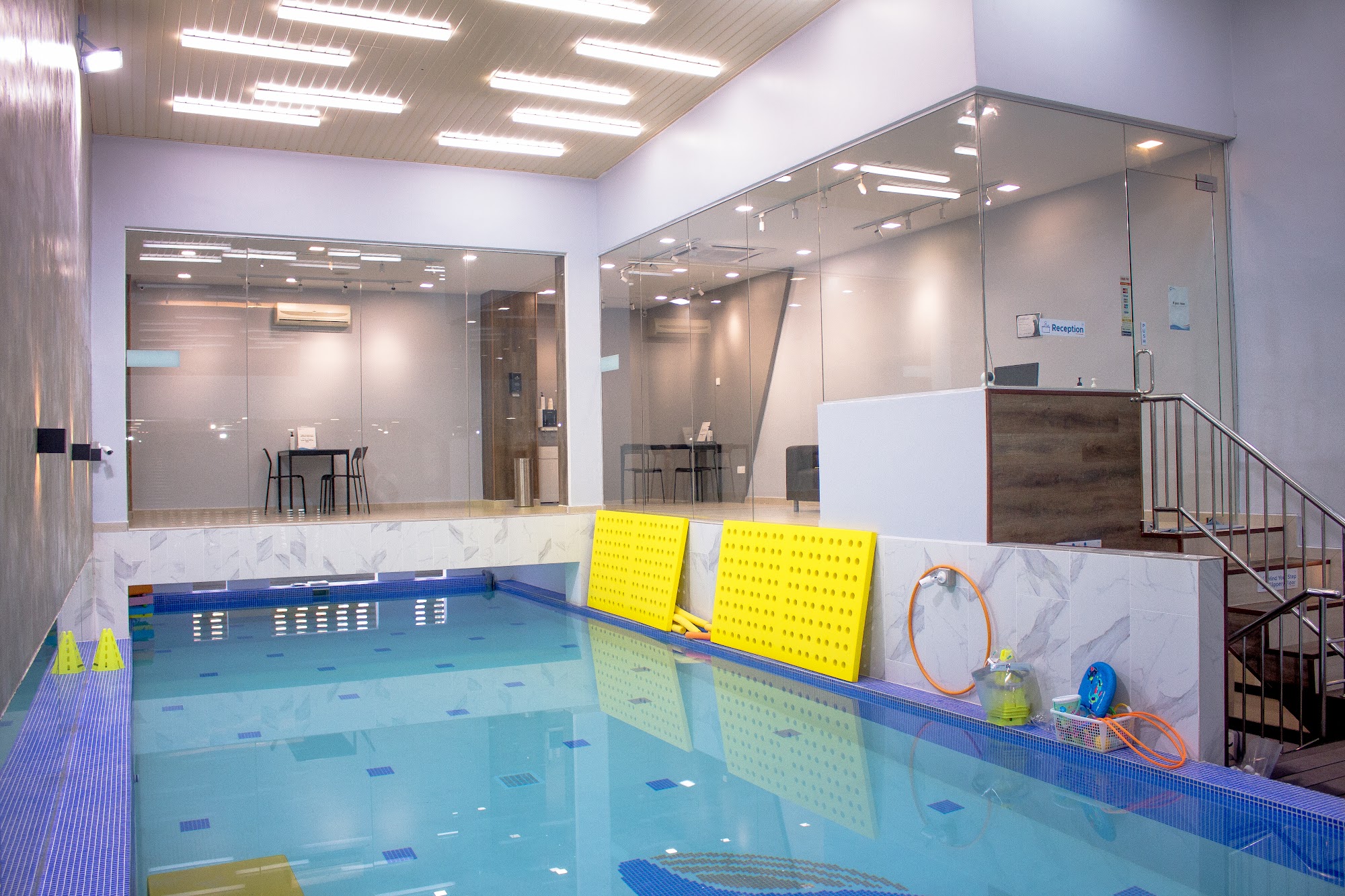 Skywhale Ara Damansara branch pool and reception, with glass-walled viewing lounge and staircase to the upper level