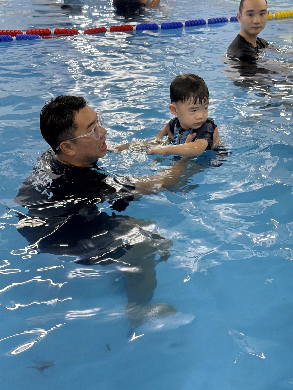 Coach guiding a young child in the pool